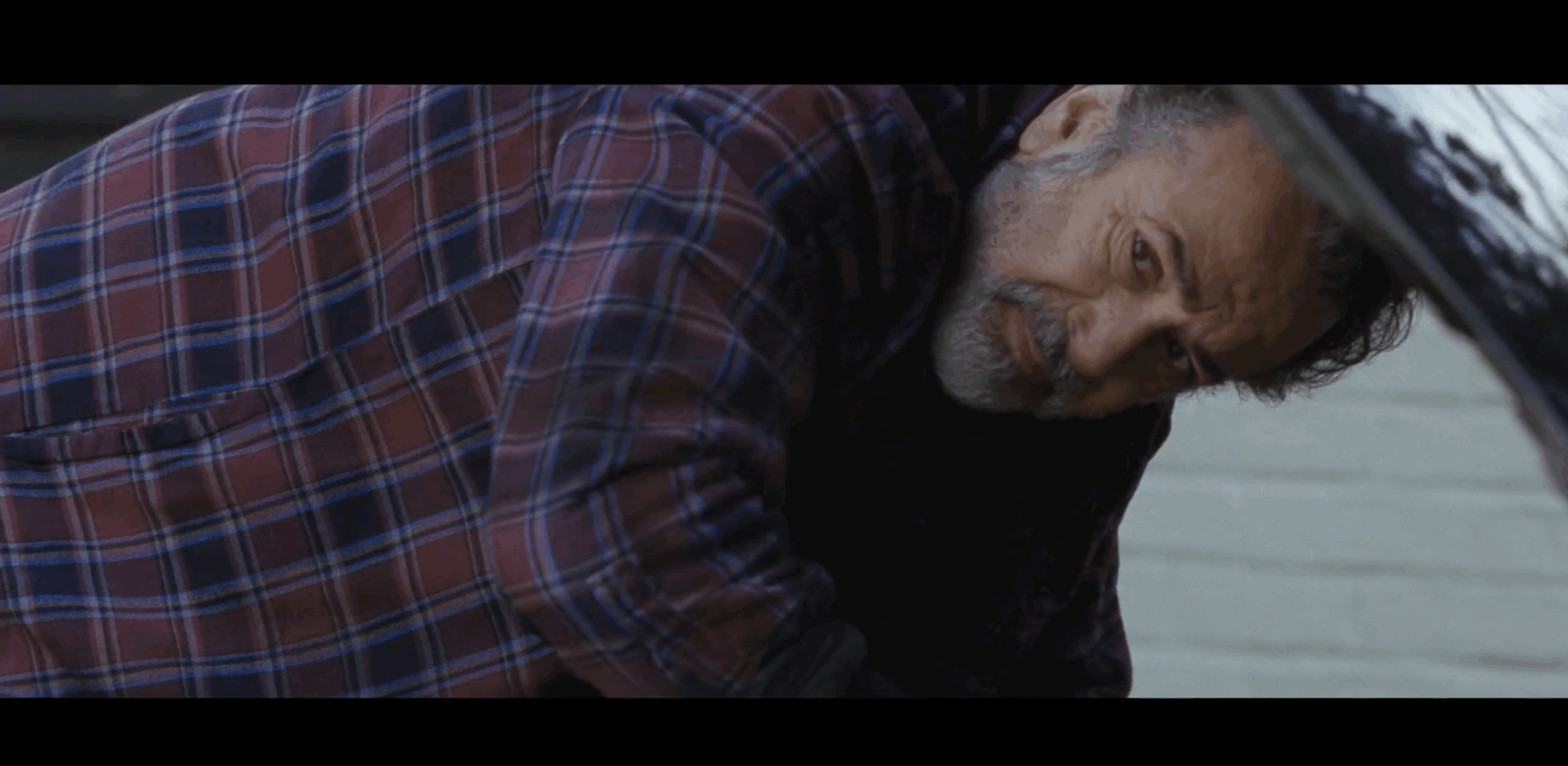 Screenshot from Stand up to Jewish Hate campaign with middle aged bearded man wearing a flannel working on the engine of a truck