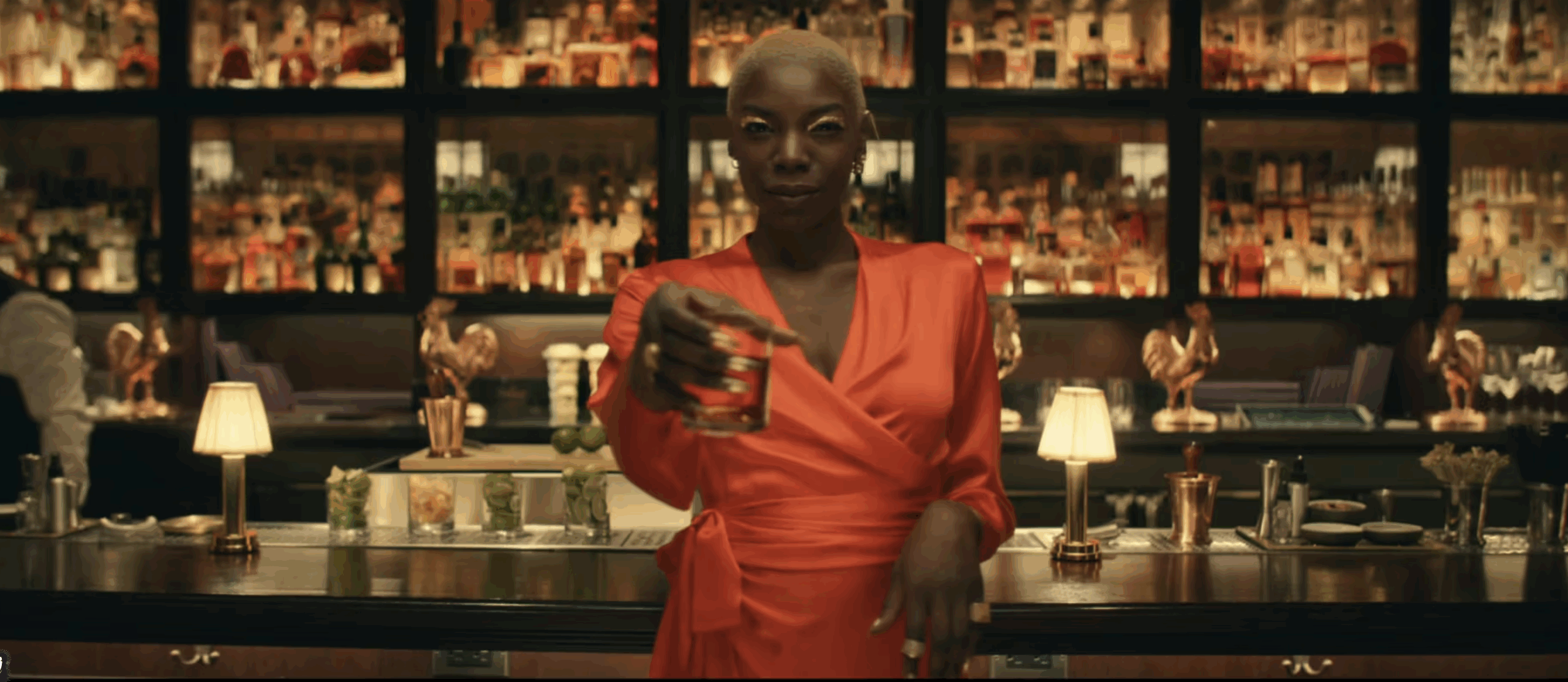 Screenshot from the "Lots O' Spots" campaign featuring a woman holding a rocks glass standing in front of a serving bar