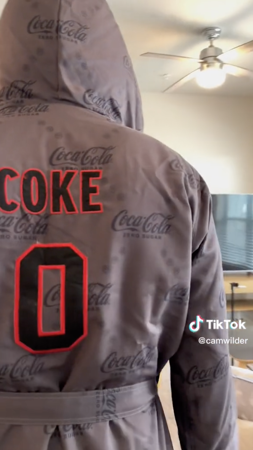 Screenshot of TikTok video featuring Coca-Cola branded boxing robe with The name COKE and a zero printed on the back